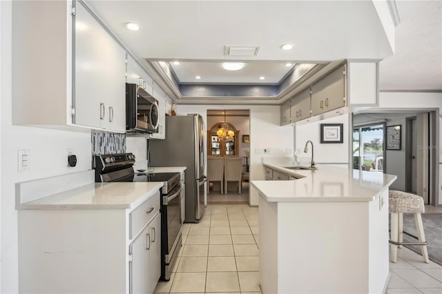 965 E Gondola Dr, Venice, FL 34293 - kitchen with stainless steel appliances, light tile patterned flooring, light countertops, a raised ceiling, and recessed lighting