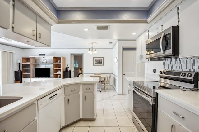 965 E Gondola Dr, Venice, FL 34293 - kitchen featuring appliances with stainless steel finishes, light countertops, light tile patterned floors, decorative backsplash, and a chandelier