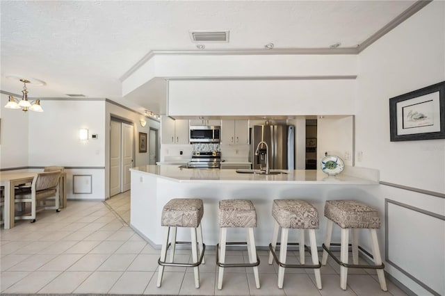 965 E Gondola Dr, Venice, FL 34293 - kitchen featuring stainless steel appliances, a peninsula, a breakfast bar area, light countertops, and ornamental molding