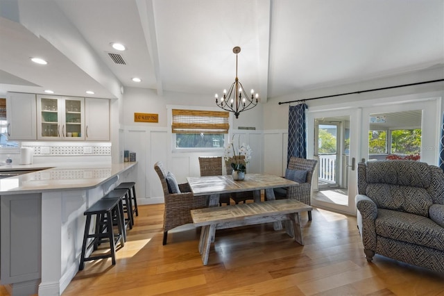 221 85th St, Holmes Beach, FL 34217 - dining room featuring plenty of natural light, light wood finished floors, a chandelier, a decorative wall, and wainscoting