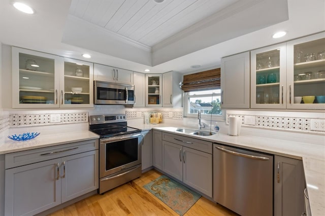 221 85th St, Holmes Beach, FL 34217 - kitchen featuring appliances with stainless steel finishes, a sink, gray cabinets, crown molding, and decorative backsplash