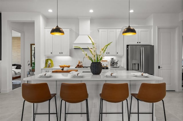 4407 Big Woods Way, Parrish, FL 34219 - kitchen featuring stainless steel refrigerator with ice dispenser, custom range hood, white cabinetry, a breakfast bar area, and a center island with sink