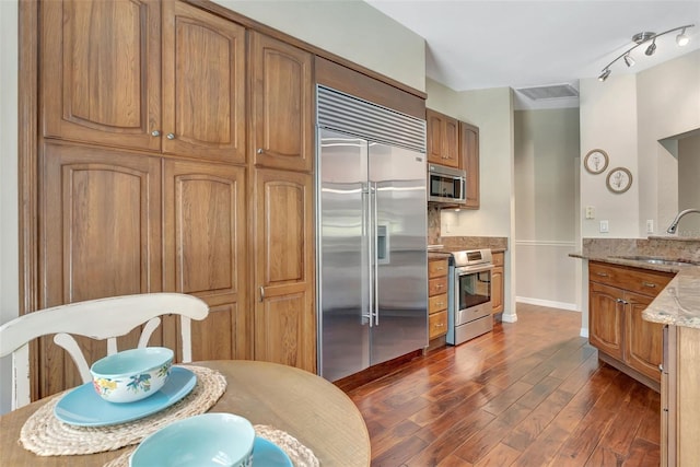 4322 Concert St, Port Charlotte, FL 33948 - kitchen featuring appliances with stainless steel finishes, a sink, light stone countertops, dark wood-style floors, and brown cabinets