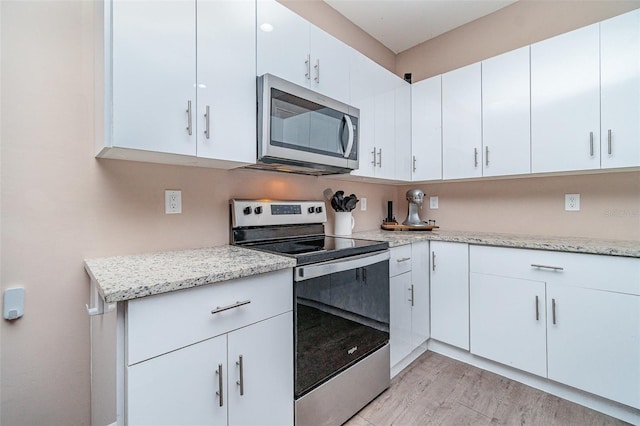 1229 Zinnia Loop, Labelle, FL 33935 - kitchen with appliances with stainless steel finishes, light wood-type flooring, light stone countertops, and white cabinetry