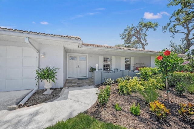 572 Commonwealth Ln, Sarasota, FL 34242 - view of front of home featuring covered porch, a tile roof, stucco siding, and an attached garage