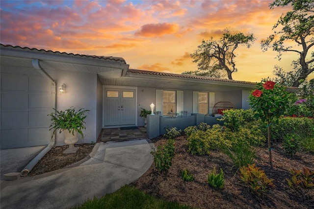 572 Commonwealth Ln, Sarasota, FL 34242 - property entrance with a porch, stucco siding, a tiled roof, and a garage