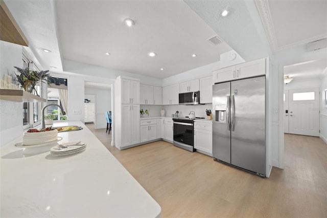 572 Commonwealth Ln, Sarasota, FL 34242 - kitchen with stainless steel appliances, a sink, light wood-style floors, light countertops, and white cabinetry