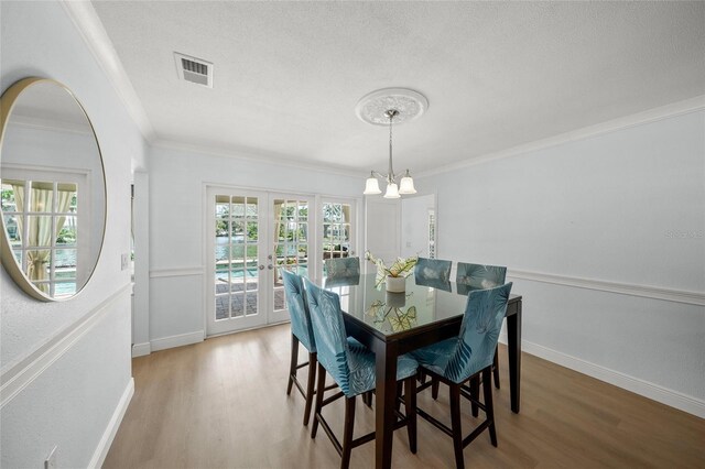 572 Commonwealth Ln, Sarasota, FL 34242 - dining area with wood finished floors, crown molding, baseboards, a chandelier, and a textured ceiling