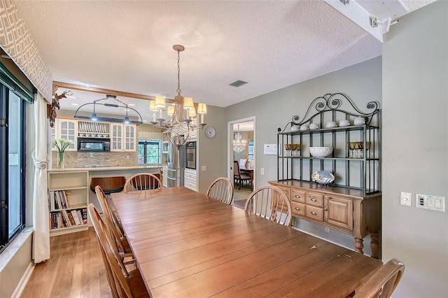 4917 Leatha Ln, Sarasota, FL 34232 - dining area featuring a chandelier, light wood finished floors, and a textured ceiling