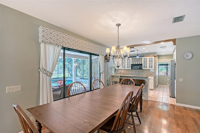 4917 Leatha Ln, Sarasota, FL 34232 - dining area with a chandelier, a textured ceiling, light wood-type flooring, and baseboards