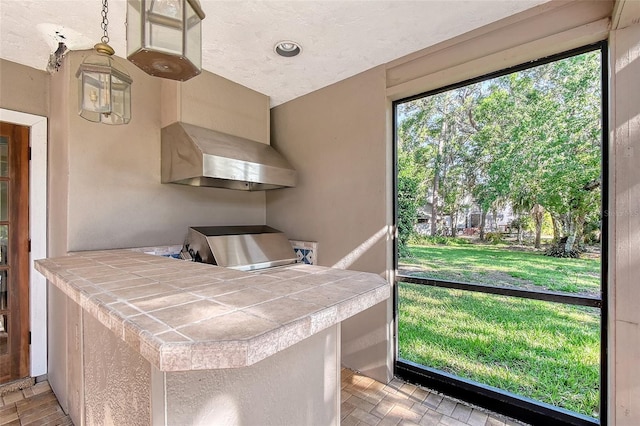 4917 Leatha Ln, Sarasota, FL 34232 - kitchen featuring tile counters and wall chimney range hood
