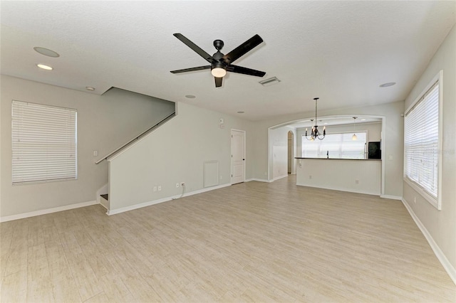 5420 River Sound Ter, Bradenton, FL 34208 - unfurnished living room with light wood finished floors, a ceiling fan, arched walkways, a chandelier, and a textured ceiling