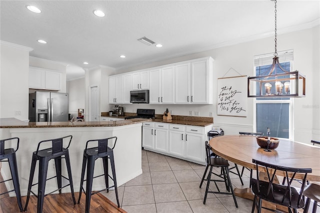 6032 36th Ct E, Ellenton, FL 34222 - kitchen featuring appliances with stainless steel finishes, crown molding, a breakfast bar, white cabinetry, and dark stone countertops