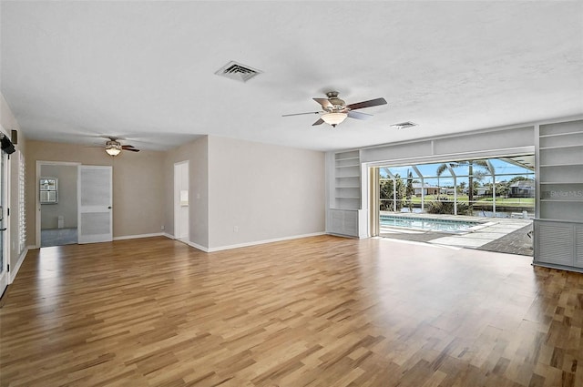 149 Small St SE, Port Charlotte, FL 33952 - unfurnished living room featuring a ceiling fan, built in shelves, light wood finished floors, baseboards, and a sunroom