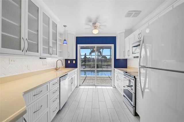 149 Small St SE, Port Charlotte, FL 33952 - kitchen with appliances with stainless steel finishes, a sink, tasteful backsplash, white cabinets, and glass insert cabinets