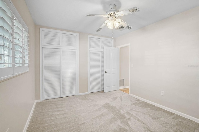 149 Small St SE, Port Charlotte, FL 33952 - unfurnished bedroom with multiple closets, baseboards, carpet floors, and a ceiling fan