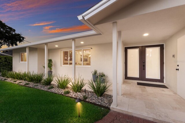 5581 Shadow Lawn Dr, Sarasota, FL 34242 - exterior entry at dusk with stucco siding and french doors