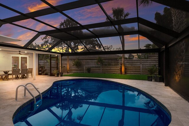 5581 Shadow Lawn Dr, Sarasota, FL 34242 - pool at dusk with a patio, glass enclosure, a ceiling fan, and outdoor dining area
