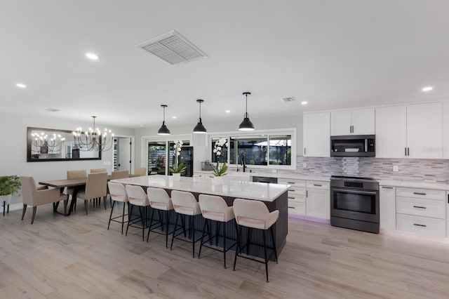 5581 Shadow Lawn Dr, Sarasota, FL 34242 - kitchen featuring appliances with stainless steel finishes, backsplash, a kitchen bar, white cabinetry, and recessed lighting