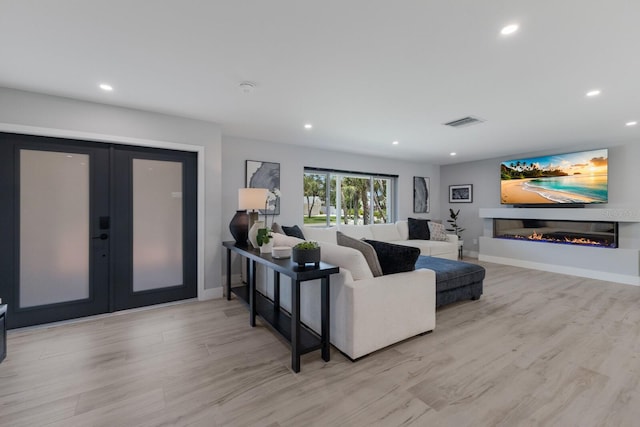 5581 Shadow Lawn Dr, Sarasota, FL 34242 - living room with light wood-type flooring, a glass covered fireplace, french doors, recessed lighting, and baseboards