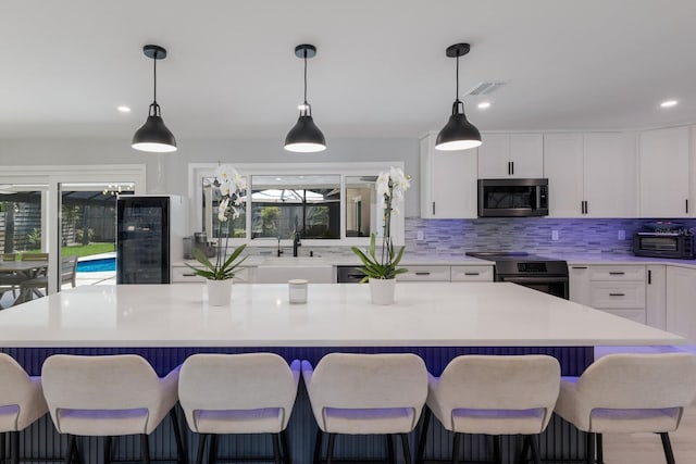 5581 Shadow Lawn Dr, Sarasota, FL 34242 - kitchen with stainless steel appliances, wine cooler, decorative backsplash, plenty of natural light, and recessed lighting