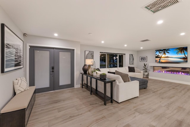 5581 Shadow Lawn Dr, Sarasota, FL 34242 - living area featuring french doors, recessed lighting, light wood-style flooring, a glass covered fireplace, and baseboards