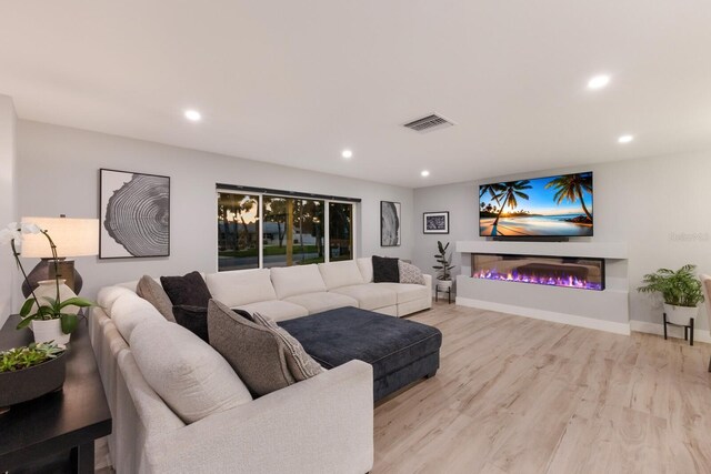 5581 Shadow Lawn Dr, Sarasota, FL 34242 - living room with recessed lighting, light wood-style flooring, a glass covered fireplace, and baseboards