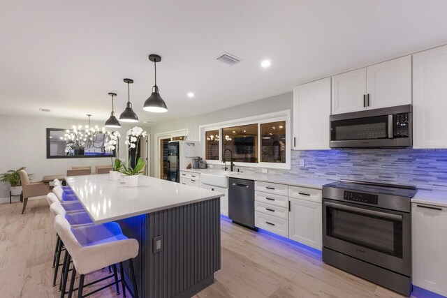 5581 Shadow Lawn Dr, Sarasota, FL 34242 - kitchen featuring appliances with stainless steel finishes, a sink, white cabinetry, backsplash, and recessed lighting