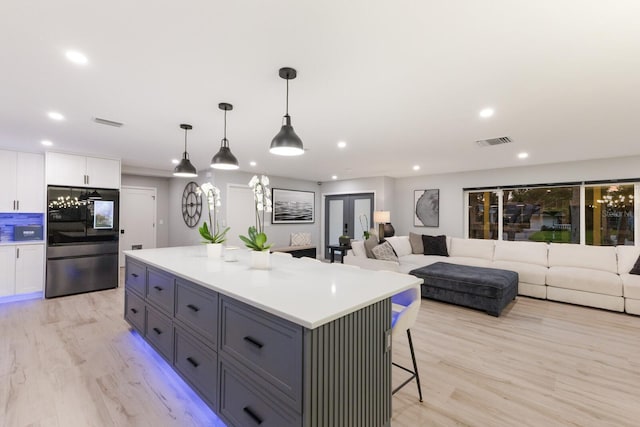 5581 Shadow Lawn Dr, Sarasota, FL 34242 - kitchen featuring smart refrigerator, white cabinets, recessed lighting, a center island, and a kitchen breakfast bar