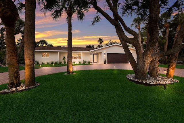 5581 Shadow Lawn Dr, Sarasota, FL 34242 - ranch-style home featuring decorative driveway, an attached garage, stucco siding, and a yard