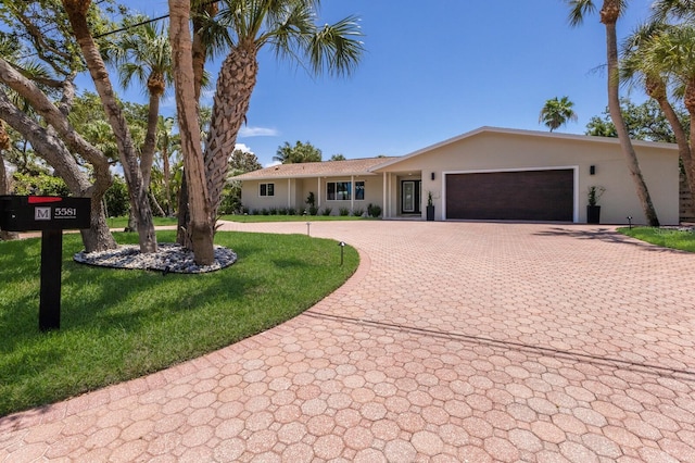 5581 Shadow Lawn Dr, Sarasota, FL 34242 - ranch-style home with decorative driveway, stucco siding, an attached garage, and a front lawn