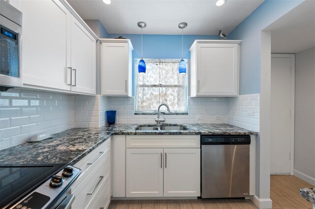 110 Vista Hermosa Cir Unit 302B, Sarasota, FL 34242 - kitchen featuring appliances with stainless steel finishes, a sink, white cabinets, light wood-style floors, and dark stone countertops
