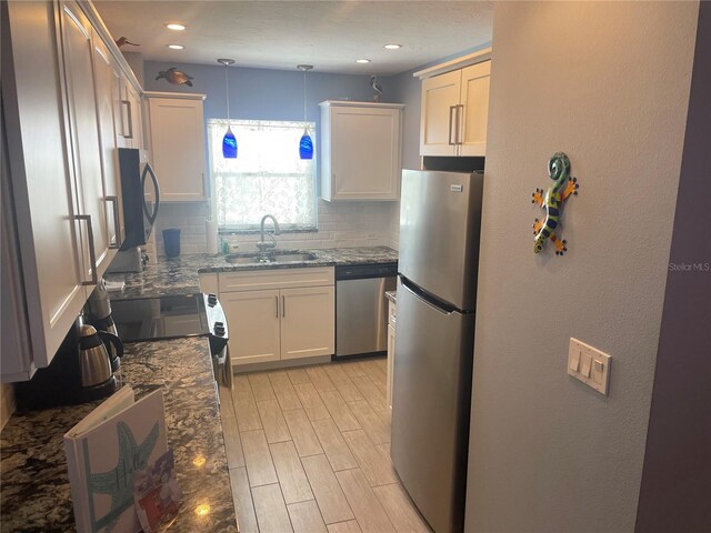 110 Vista Hermosa Cir Unit 302B, Sarasota, FL 34242 - kitchen with stainless steel appliances, a sink, decorative backsplash, dark stone countertops, and hanging light fixtures