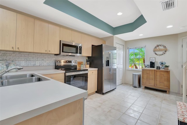 1216 Rio De Janeiro Ave Unit 306, Punta Gorda, FL 33983 - kitchen featuring appliances with stainless steel finishes, light brown cabinetry, a sink, decorative backsplash, and light countertops