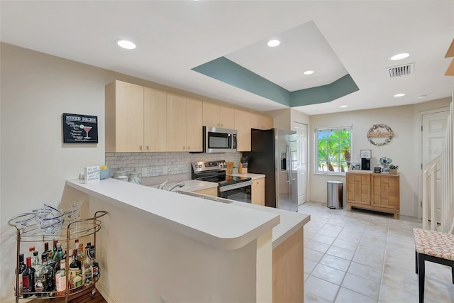 1216 Rio De Janeiro Ave Unit 306, Punta Gorda, FL 33983 - kitchen with appliances with stainless steel finishes, light brown cabinetry, light countertops, a peninsula, and tasteful backsplash