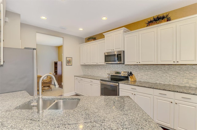 12229 Stuart Dr, Venice, FL 34293 - kitchen featuring appliances with stainless steel finishes, a sink, decorative backsplash, white cabinetry, and recessed lighting