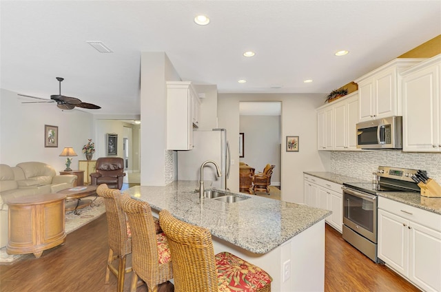 12229 Stuart Dr, Venice, FL 34293 - kitchen featuring stainless steel appliances, a sink, tasteful backsplash, white cabinetry, and open floor plan