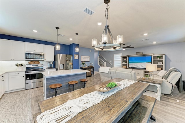 8940 Royal River Cir, Parrish, FL 34219 - dining space featuring stairs, recessed lighting, light wood finished floors, a chandelier, and a ceiling fan
