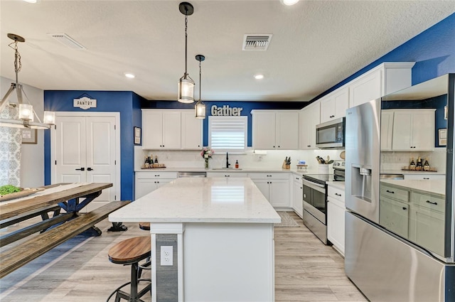 8940 Royal River Cir, Parrish, FL 34219 - kitchen featuring stainless steel appliances, a center island, white cabinets, recessed lighting, and a breakfast bar