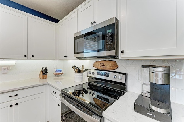 8940 Royal River Cir, Parrish, FL 34219 - kitchen featuring stainless steel appliances, decorative backsplash, white cabinetry, and light stone counters