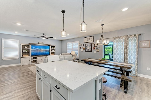 8940 Royal River Cir, Parrish, FL 34219 - kitchen with baseboards, light wood-style floors, a kitchen island, ceiling fan, and white cabinetry