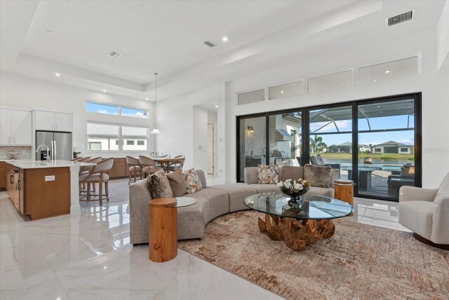 8982 Baroque Ter, Sarasota, FL 34240 - living room with a tray ceiling, light marble finish flooring, recessed lighting, and a high ceiling