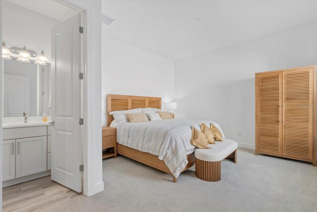 8982 Baroque Ter, Sarasota, FL 34240 - bedroom featuring a sink, ensuite bath, light carpet, and baseboards