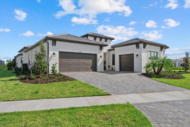 8982 Baroque Ter, Sarasota, FL 34240 - prairie-style home featuring an attached garage, decorative driveway, a front lawn, stucco siding, and a tiled roof