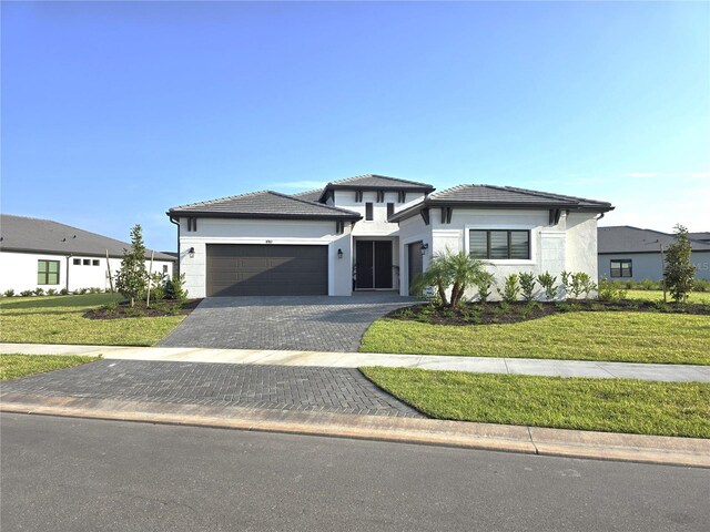 8982 Baroque Ter, Sarasota, FL 34240 - prairie-style house featuring a garage, a front yard, decorative driveway, and stucco siding