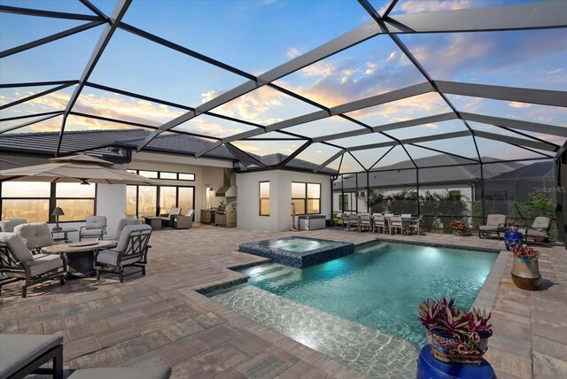 8982 Baroque Ter, Sarasota, FL 34240 - pool at dusk featuring a patio, an outdoor living space with a fire pit, a pool with connected hot tub, and glass enclosure