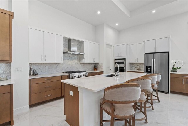 8982 Baroque Ter, Sarasota, FL 34240 - kitchen featuring stainless steel appliances, a sink, light marble finish flooring, wall chimney exhaust hood, and a kitchen bar