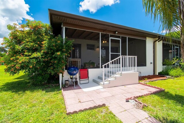 3203 Riverside Dr Unit B, Punta Gorda, FL 33950 - rear view of house featuring a patio area, a sunroom, a yard, and stucco siding