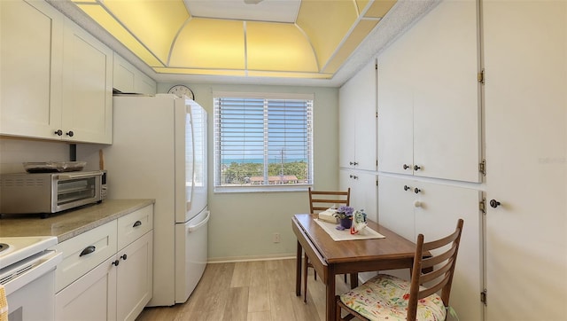 8897 Midnight Pass Rd Unit 407, Sarasota, FL 34242 - kitchen featuring freestanding refrigerator, light wood-style flooring, white cabinetry, light countertops, and baseboards