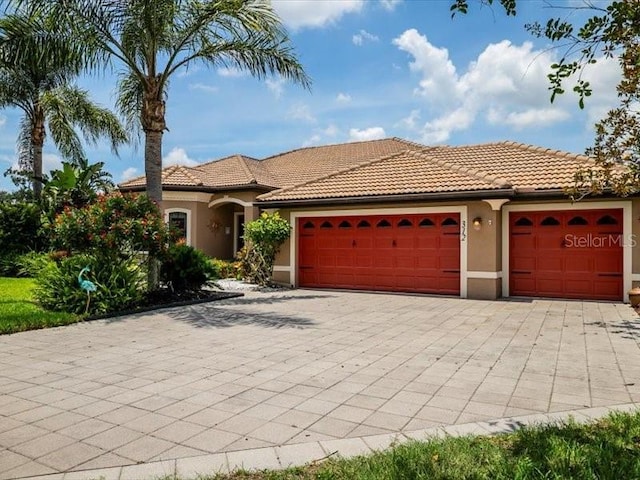 312 148th Ct NE, Bradenton, FL 34212 - mediterranean / spanish home featuring an attached garage, decorative driveway, stucco siding, and a tiled roof